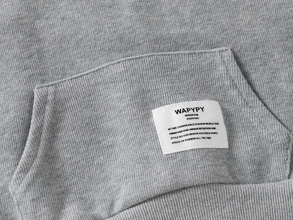 Close-up of gray kid's hooded sweatshirt with white stripes and fleece lining, focusing on label detail.